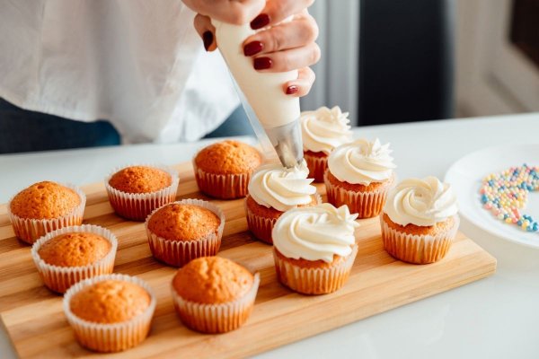 Lady icing cupcakes with piping bag